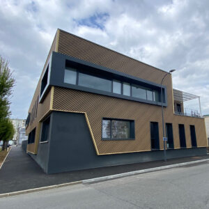 Façade de bâtiment avec bardage en acier effet bois et finitions contemporaines.