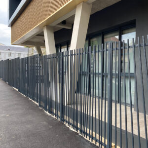 Clôture barreaudée design devant un bâtiment moderne.