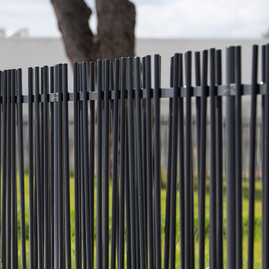 Clôture barreaudée en acier thermolaqué gris anthracite, avec barreaux verticaux décalés, installée en extérieur.