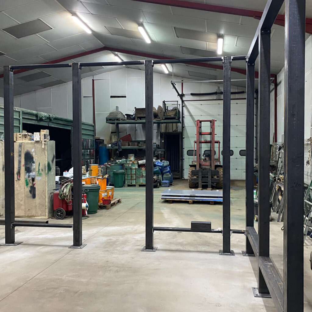 Ossature métallique en cours de fabrication dans un atelier de métallerie, composée de poteaux en acier fixés sur platines, destinée à un futur aménagement.