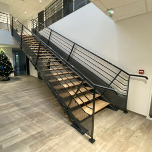 Escalier intérieur en métal avec marches bois et garde-corps noir.