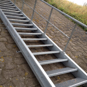 Escalier métallique incliné avec main courante, installé sur un chemin pavé.