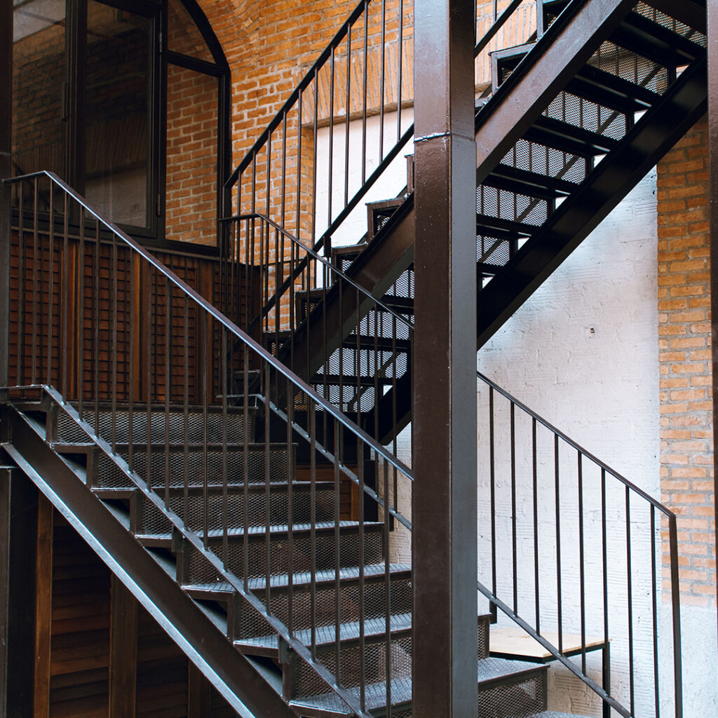 Escalier intérieur en métal avec structure tubulaire et garde-corps à barreaux verticaux.
