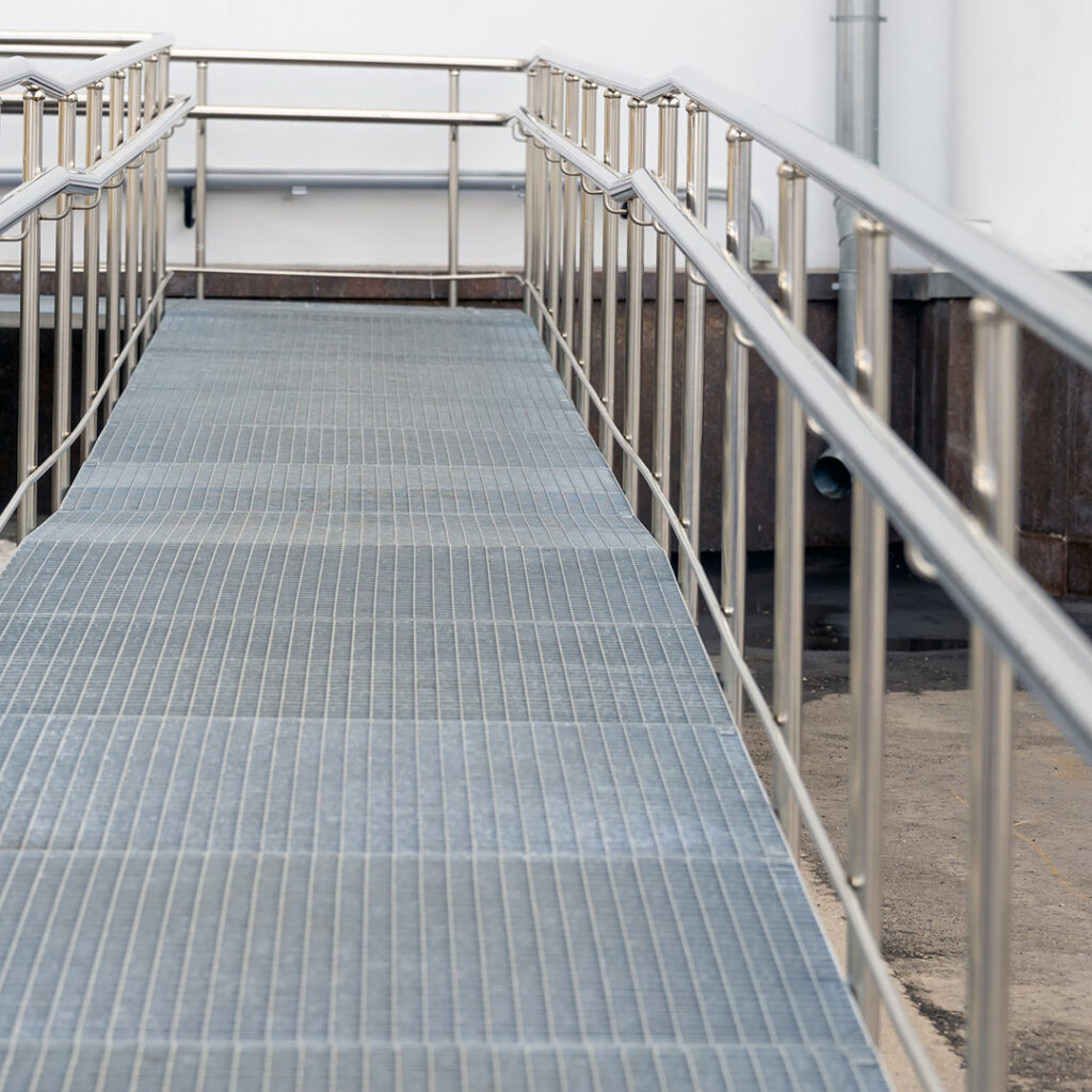 Rampe d’accès avec garde-corps inox industriel à lisses horizontales, installée sur caillebotis pour sécuriser un cheminement technique.