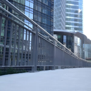 Garde-corps métallique sur une passerelle urbaine, au cœur d’un quartier d’affaires moderne.
