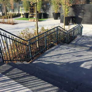 Mains courantes métalliques installées sur un escalier extérieur en milieu urbain.