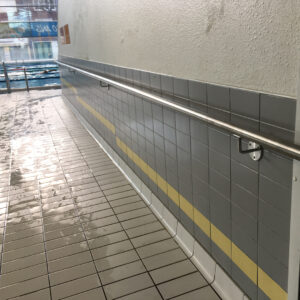 Main courante en inox installée le long d’un mur carrelé dans une piscine.