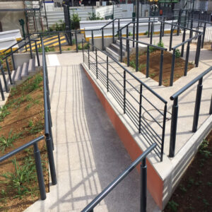 Rampes d'accès équipées de mains courantes métalliques dans un aménagement paysager urbain.