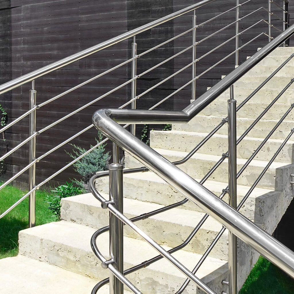Garde-corps à barreaudage horizontal avec mains courantes en inox, installé le long d’un escalier extérieur en béton, dans un aménagement paysager moderne.