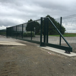 Portail coulissant grillagé vert installé sur un site industriel.